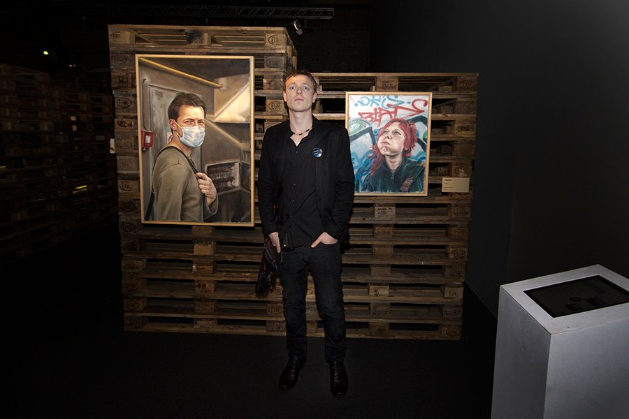 ARTIST MATEJ REJL IN FRONT OF TWO OF HIS WORKS